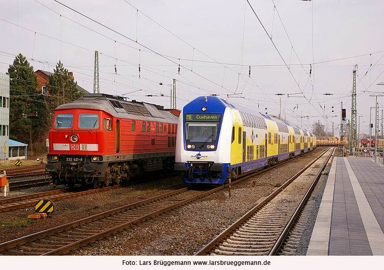 Ein Güterzug mit einer Lok der Baureihe 232 und ein Metronom im Bahnhof Stade